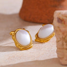 Gold earrings with white stones on a beige surface